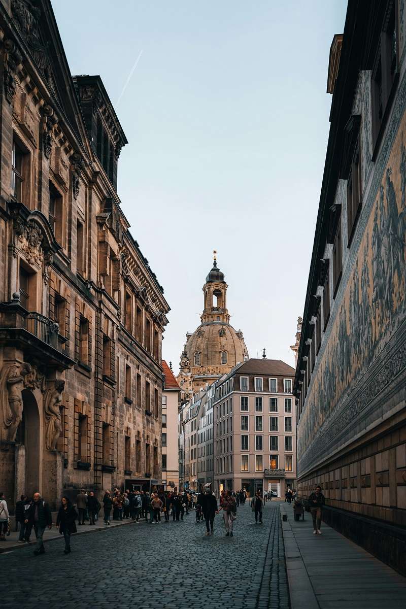 Calle adoquinada en el centro histórico de Dresde, Alemania, con la cúpula de la Frauenkirche (Iglesia de Nuestra Señora) al fondo